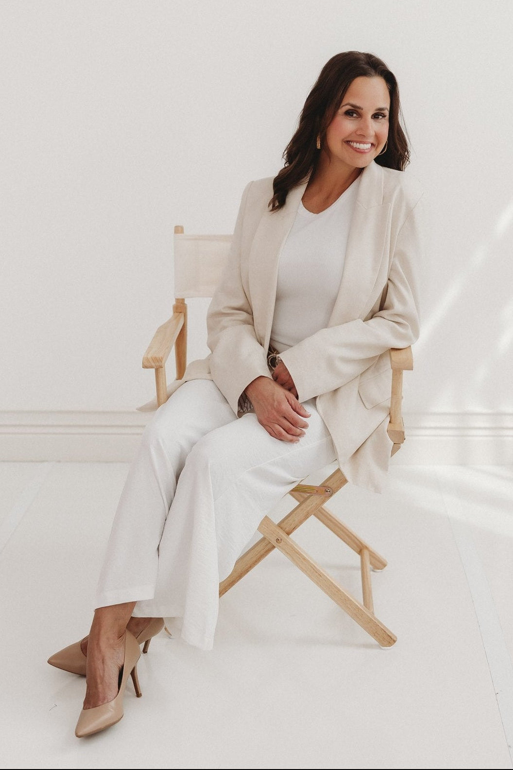 Picture of Dr. Sheena Joseph in an all beige outfit sitting on a chair for a professional picture for the brand ROOTSOPHY™