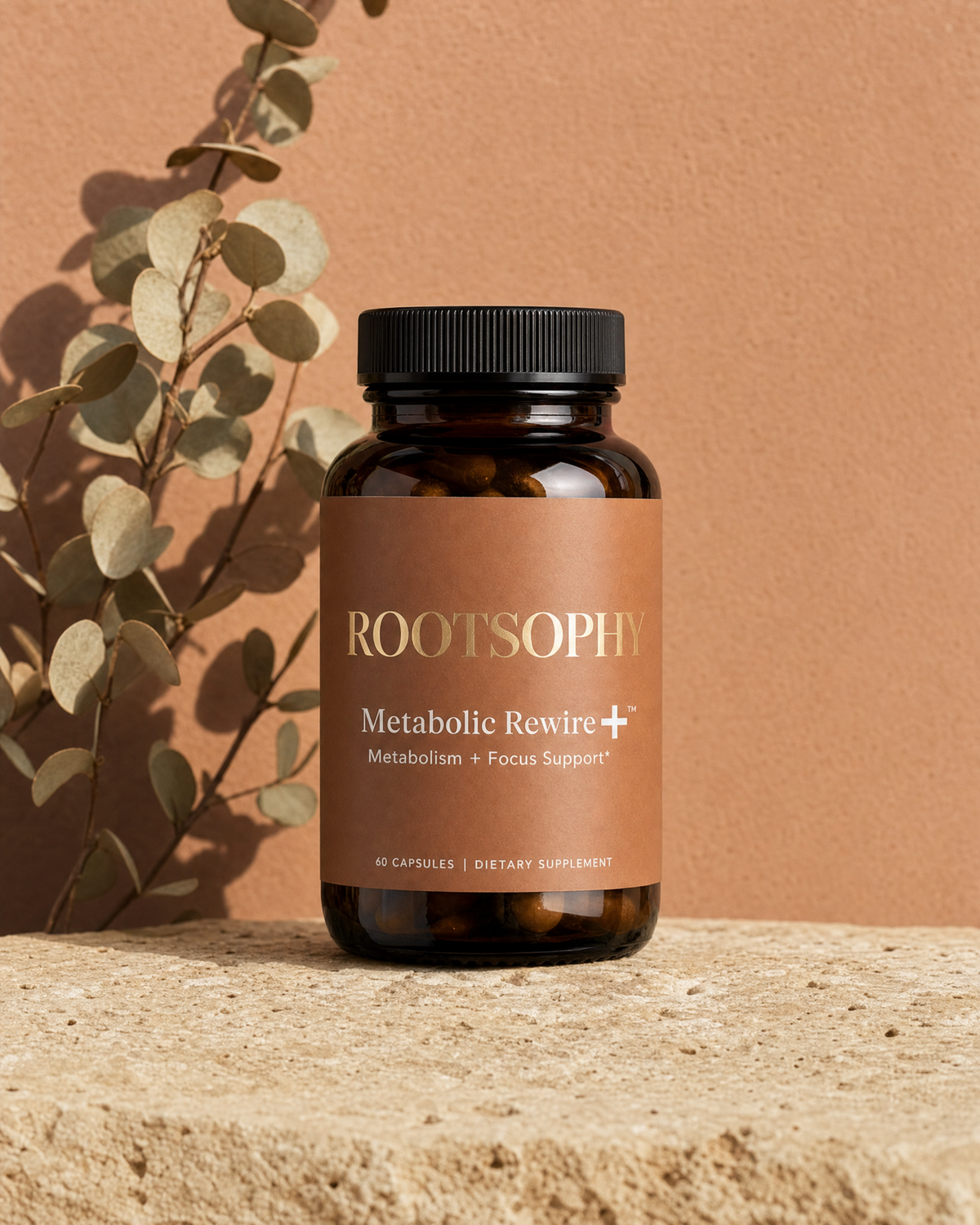 A bottle of ROOTSOPHY Metabolic Rewire+ dietary supplement capsules, set on a textured stone surface with a warm terracotta background and a decorative eucalyptus branch.
